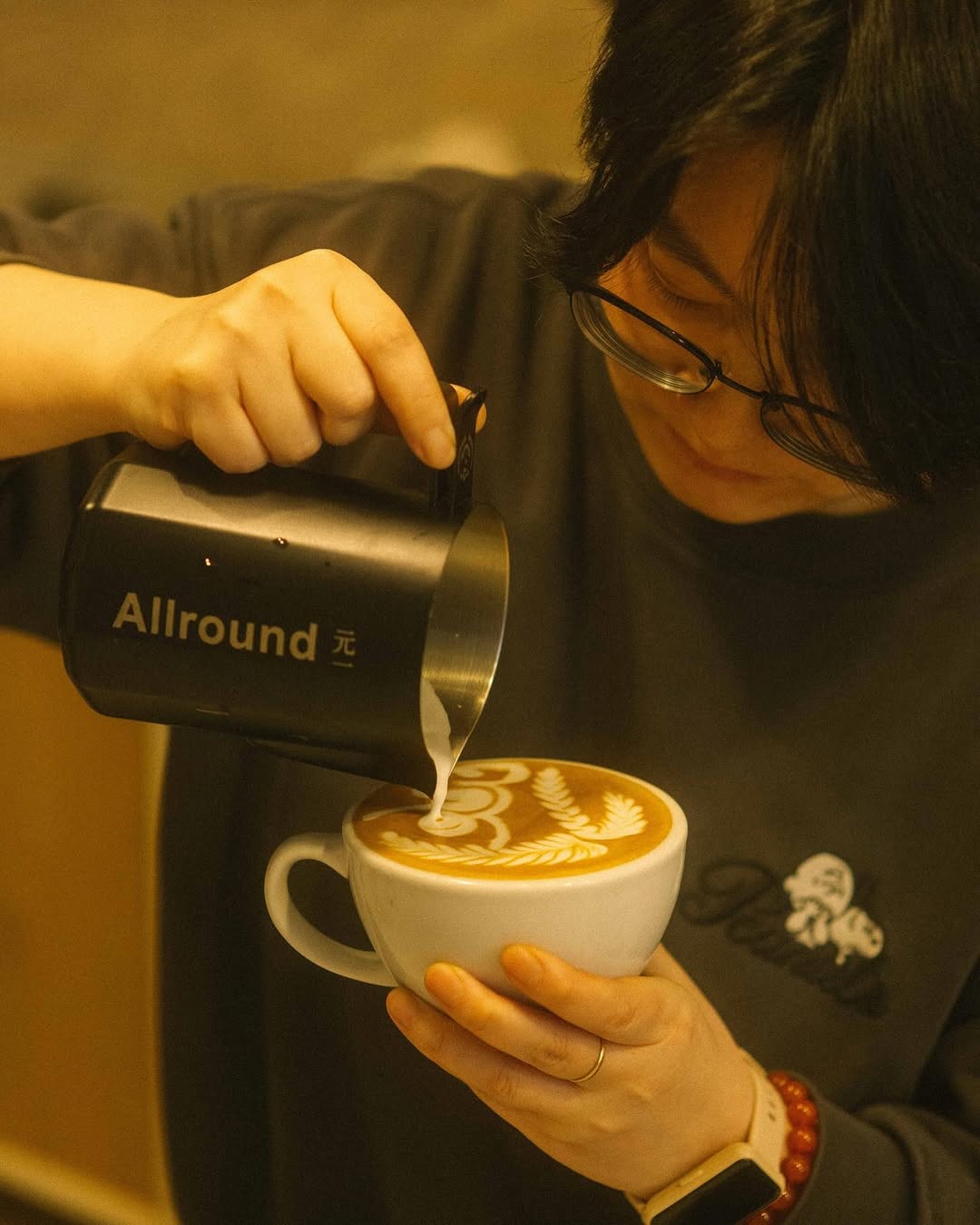A barista pouring an intricate latte-art pattern