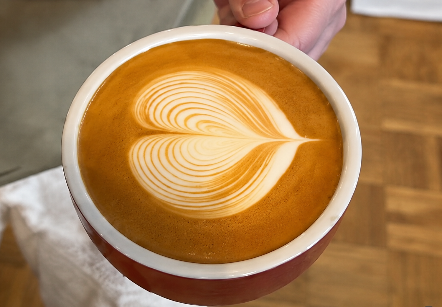 heart shaped latte art in a cup held in hand